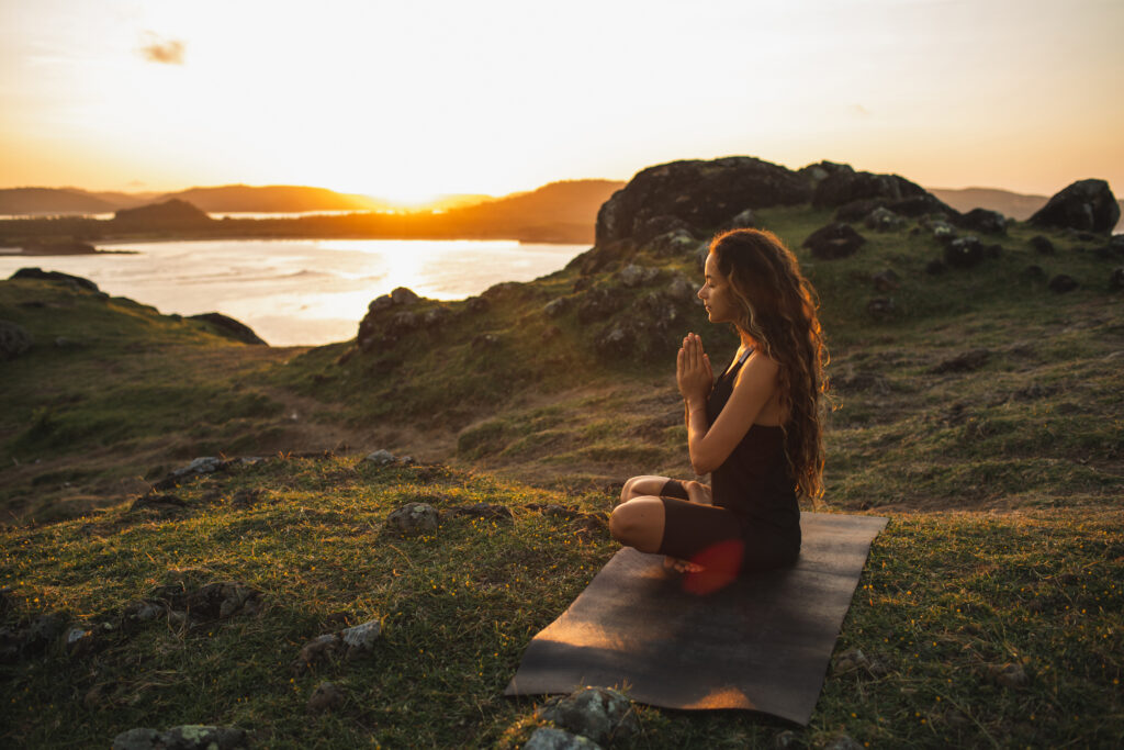 woman doing yoga alone at sunrise with mountain view. harmony with nature