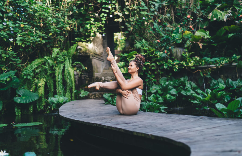 slim woman sitting on wooden bridge and doing yoga