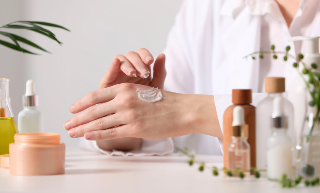 dermatologist applying cream onto hand at white table indoors, selective focus. testing cosmetic product