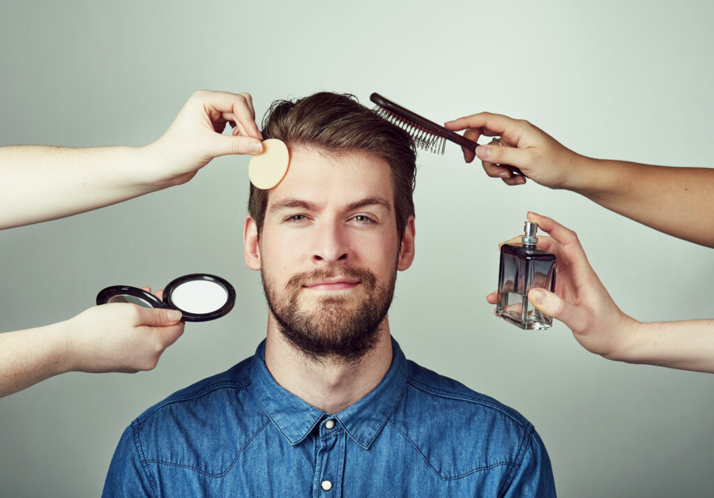 real men get makeovers. studio portrait of a young man getting a makeover against a gray background.